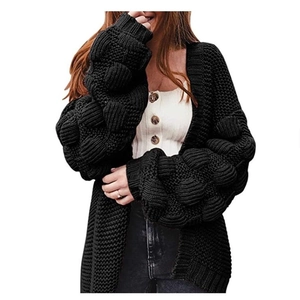 Gros plan du cardigan en grosse maille noire avec manches bouffantes à pompons 3D texturés