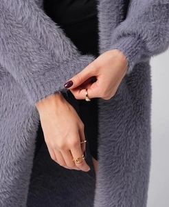 Close-up of soft purple faux mink fur texture and ribbed knit cuffs on a stylish cardigan