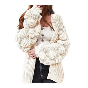 Détail de manches bouffantes en maille épaisse avec pompons sur cardigan crème