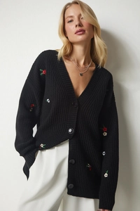 Detail der Blumenstickerei auf einer schwarzen Strickjacke mit großen Knöpfen und V-Ausschnitt