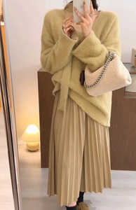 Chic long yellow faux fur sweater paired with a beige pleated skirt and plush chain bag