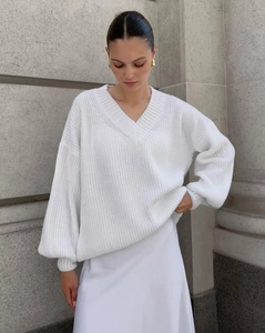 Detail of white V-neck oversized cable knit sweater with baggy lantern sleeves