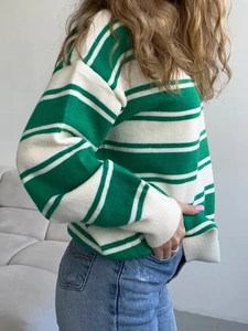 Detail view of green and white striped knit sweater with thick texture and ribbed cuffs