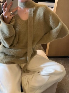 Detail of soft sage green faux mink fur sweater featuring a cozy scarf and V-neck design