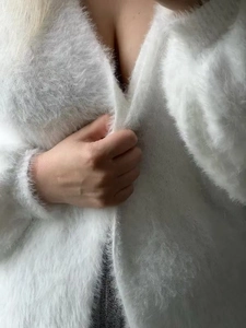 Detail of soft white faux mink fur texture on a loose V-neck knitted cardigan