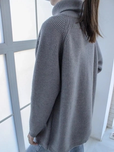 Dettaglio di un maglione grigio a collo alto con vestibilità ampia e trama morbida