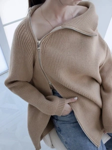 Dettaglio del maglione in maglia grossa kaki con colletto con cerniera diagonale asimmetrica