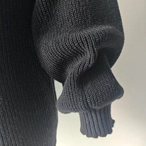 Detailed close-up of black knit sweater ribbed cuffs with elegant lantern sleeve design
