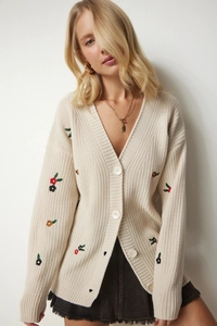 Detailaufnahme der cremefarbenen Strickjacke mit bunter Blumenstickerei und Knöpfen