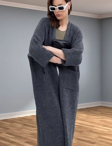 Detail view of the thick knit texture and large pocket on a dark gray oversized cardigan