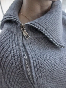 Dettaglio del collo alto grigio con zip e della spessa trama in maglia a coste