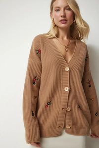 Detail der karamellfarbenen Strickjacke mit Blumenstickerei und Holzknöpfen