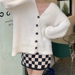 Détail du cardigan blanc en fausse fourrure de vison avec col en V et boutons noirs