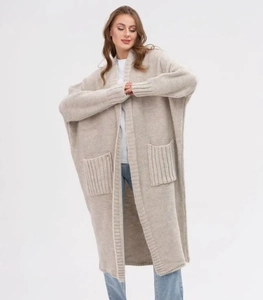 Detail of loose beige knit cardigan featuring oversized pockets and ribbed trim finish