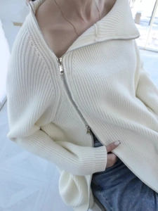 Dettaglio maglione in maglia a coste crema con zip diagonale e texture morbida