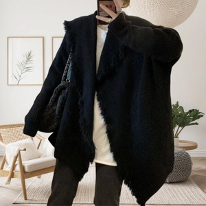 Detail of black knit cardigan featuring thick texture and dense fringe trim details