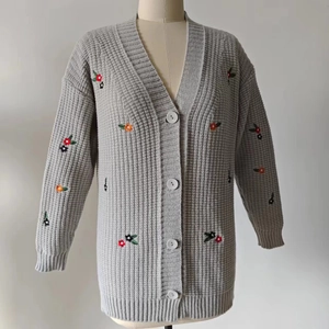 Detailaufnahme der grauen Strickjacke mit bunten Blumenstickereien und Knöpfen