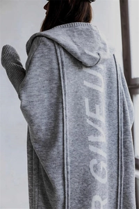 Detail of the oversized grey knit cardigan featuring white vertical back lettering