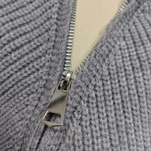 Dettaglio ravvicinato della cerniera in metallo su un maglione grigio a maglia spessa