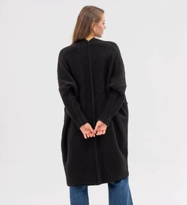 Detail view of black knit cardigan featuring vertical back seam and long ribbed cuffs