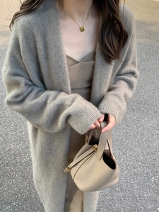 Detailed texture of thick grey knit cardigan paired with a beige leather bucket bag