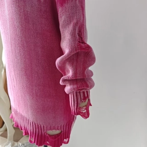 Close-up of distressed ripped details and knit texture on this pink oversized sweater