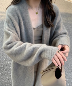 Detail shot of oatmeal knit cardigan texture with leather bucket bag and gold necklace