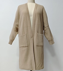 Detail of light beige knit cardigan featuring large ribbed pockets and thick textured fabric