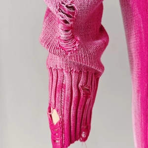 Detailed view of distressed hot pink knit sweater with ripped cuffs and worn-out texture