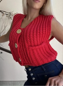 Close-up of a red knit vest featuring large textured gold buttons and a V-neckline detail