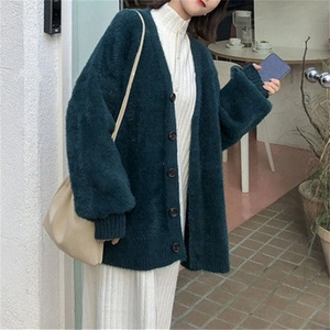 Détail du cardigan en maille vert foncé avec col en V et boutons de style urbain