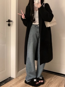 Mirror selfie showing a long black knit cardigan with jeans and fluffy slippers