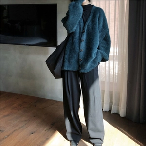 Détail d'un cardigan en maille pelucheuse vert foncé avec col en V et boutonnage simple