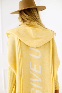 Macro shot of white knitted GIVE UP lettering on the back of a yellow hooded cardigan
