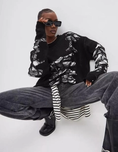 Detail of oversized distressed knit sweater with black and white contrast ripped texture