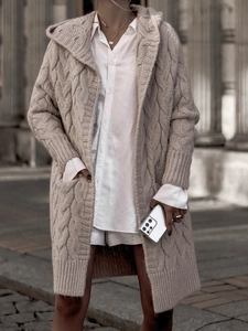 Detail of chunky cable knit texture and large pocket on a beige long hooded cardigan