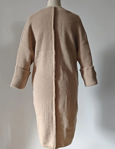 Detail view of beige knit cardigan featuring mixed rib textures and center seam stitching