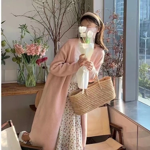 Pale pink long knit cardigan styled with a floral maxi dress and woven tote bag