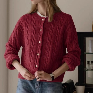 Detail of red cable-knit cardigan showing round neck and cream white buttons