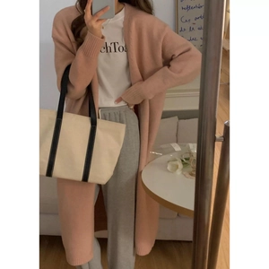 Detail of pink knitted cardigan with white t-shirt and grey trousers for casual winter style