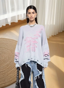 Detail of light blue distressed knit sweater with pink frayed hem and street style vibe