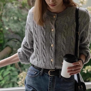 Detail of dark grey cable knit cardigan featuring premium gold buttons and ribbed cuffs