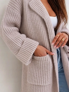 Dettaglio ravvicinato del cardigan in maglia grossa beige con trama spessa e tasca laterale