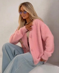 Dettaglio del cardigan rosa in finta pelliccia con trama soffice e scollo a V con bottoni