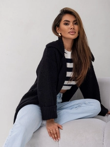 Dettaglio del cardigan nero in maglia spessa con ampio colletto e polsini risvoltati