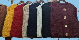 Detail of chunky knit vest featuring gold-tone buttons and front patch pockets