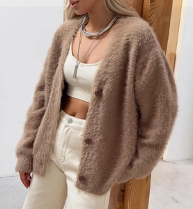 Dettaglio del cardigan in maglia sintetica effetto visone con grandi bottoni marroni