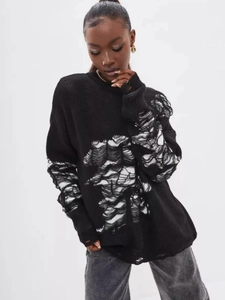 Relaxed black knit sweater with distressed white fringe details and street style look