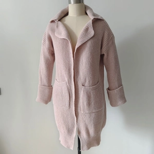 Dettaglio ravvicinato del cardigan in maglia spessa con grandi revers e tasche frontali