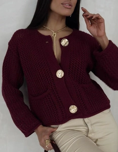 Gros plan du cardigan en tricot bordeaux avec trois gros boutons dorés gaufrés et poches
